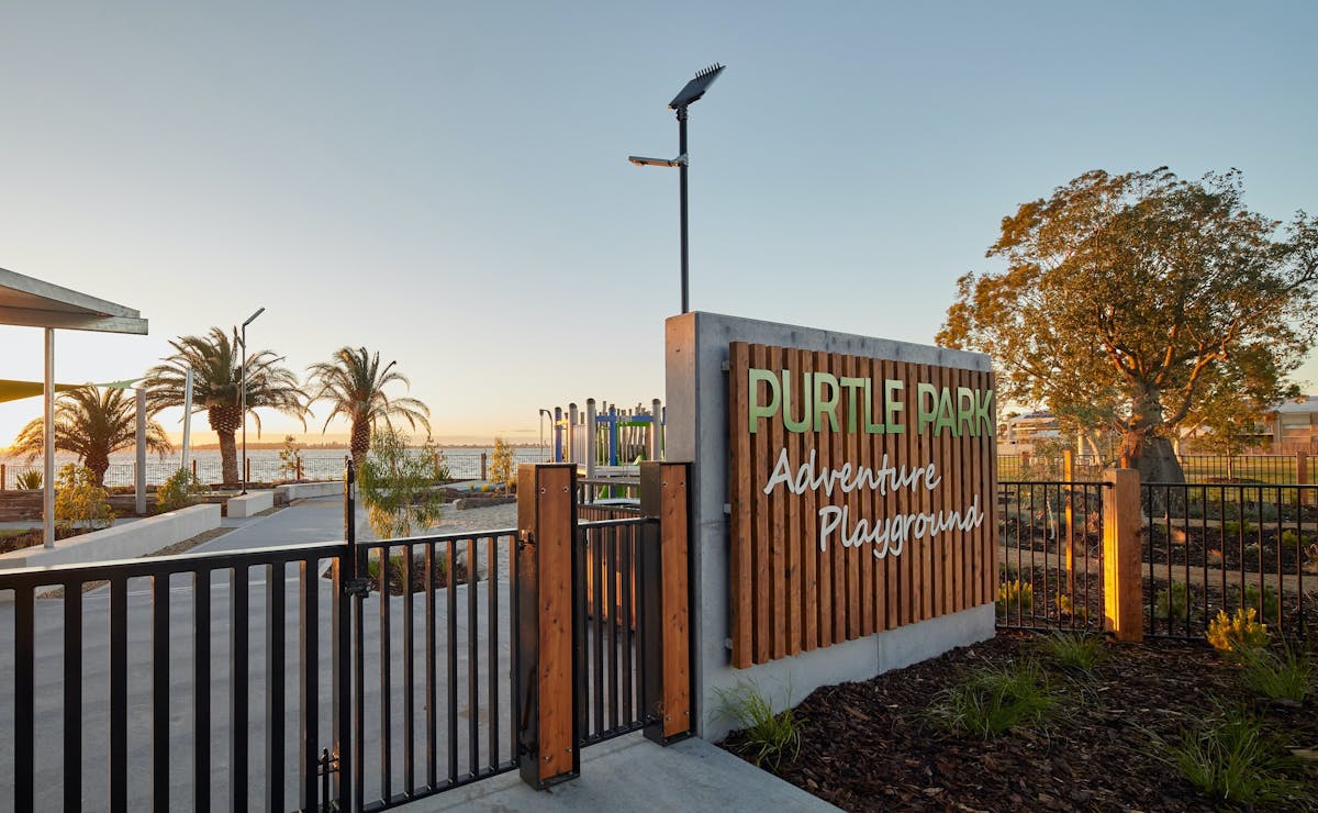 A fence and gate leading to a playground. A sign reads 