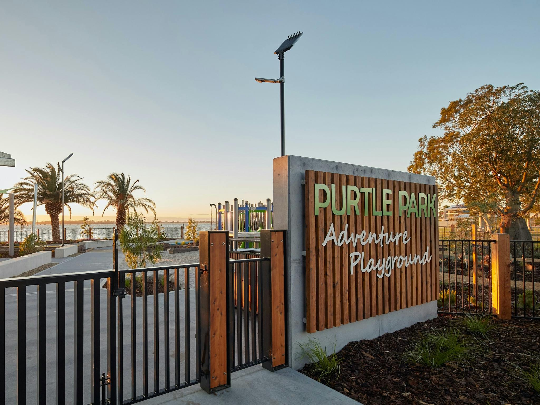 A fence and gate leading to a playground. A sign reads "Purtle Park Adventure Playground".