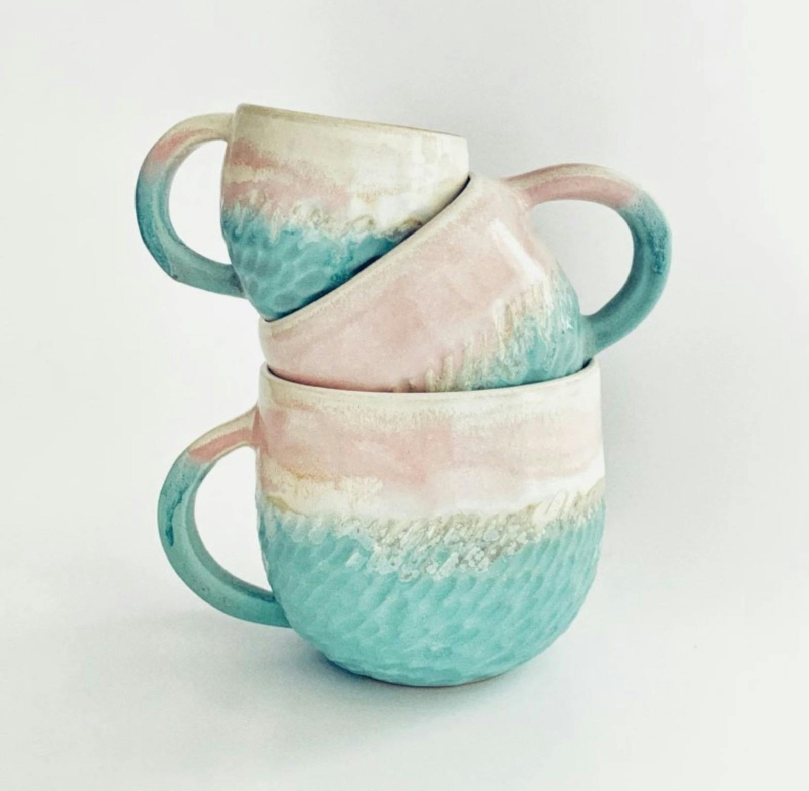 A stack of three blue and white ceramic mugs from the largest at the bottom to the smallest on top