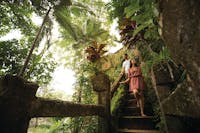 Couple walk down the grand stair case at Paronella Park taking in the tropical landscapes.