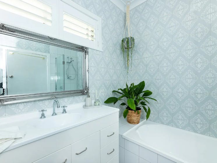 Bathroom with sage feature wall tile, bath and statement mirror