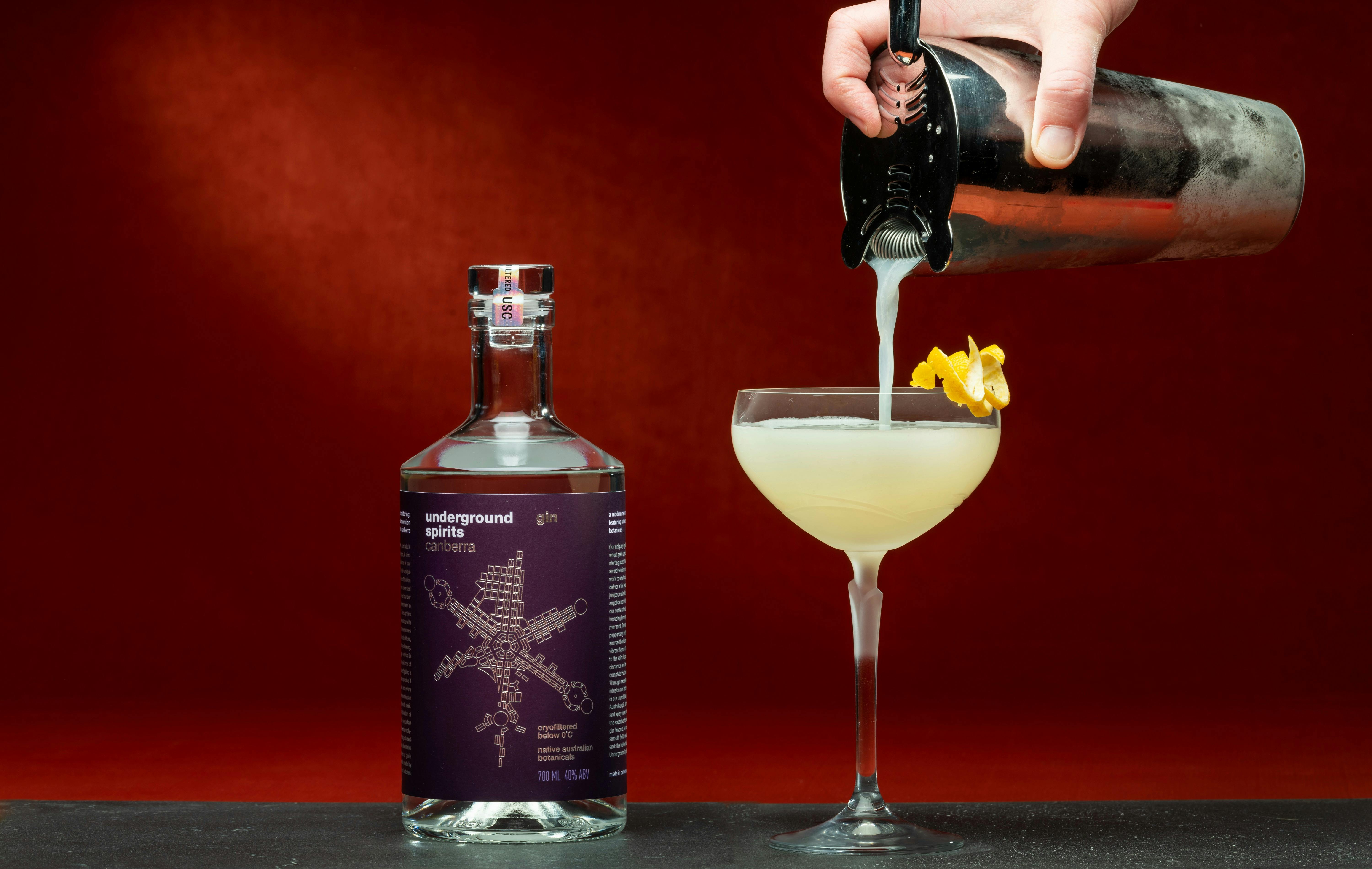 Pouring a cocktail next to a bottle of Underground Spirits Gin