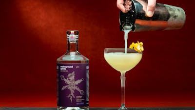 Pouring a cocktail next to a bottle of Underground Spirits Gin