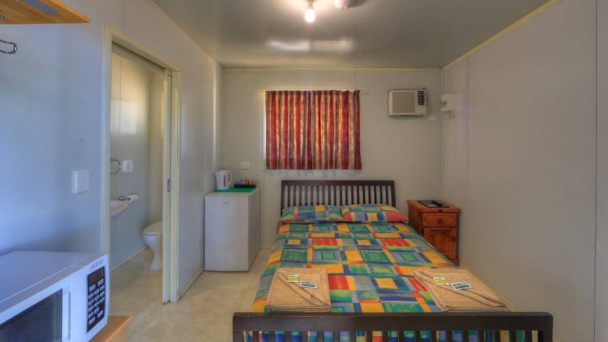 Room with ensuite has a double bed, bar fridge, microwave, tv and airconditioning