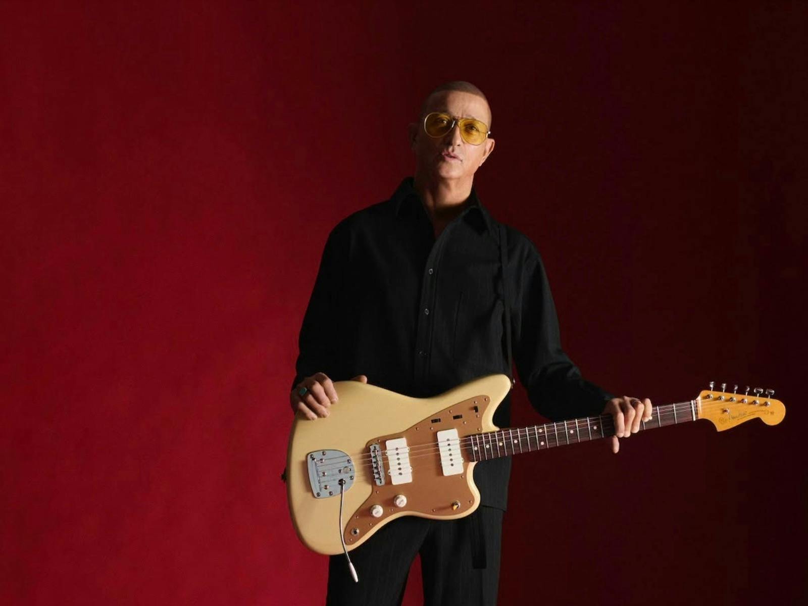 man with a guitar on a red background