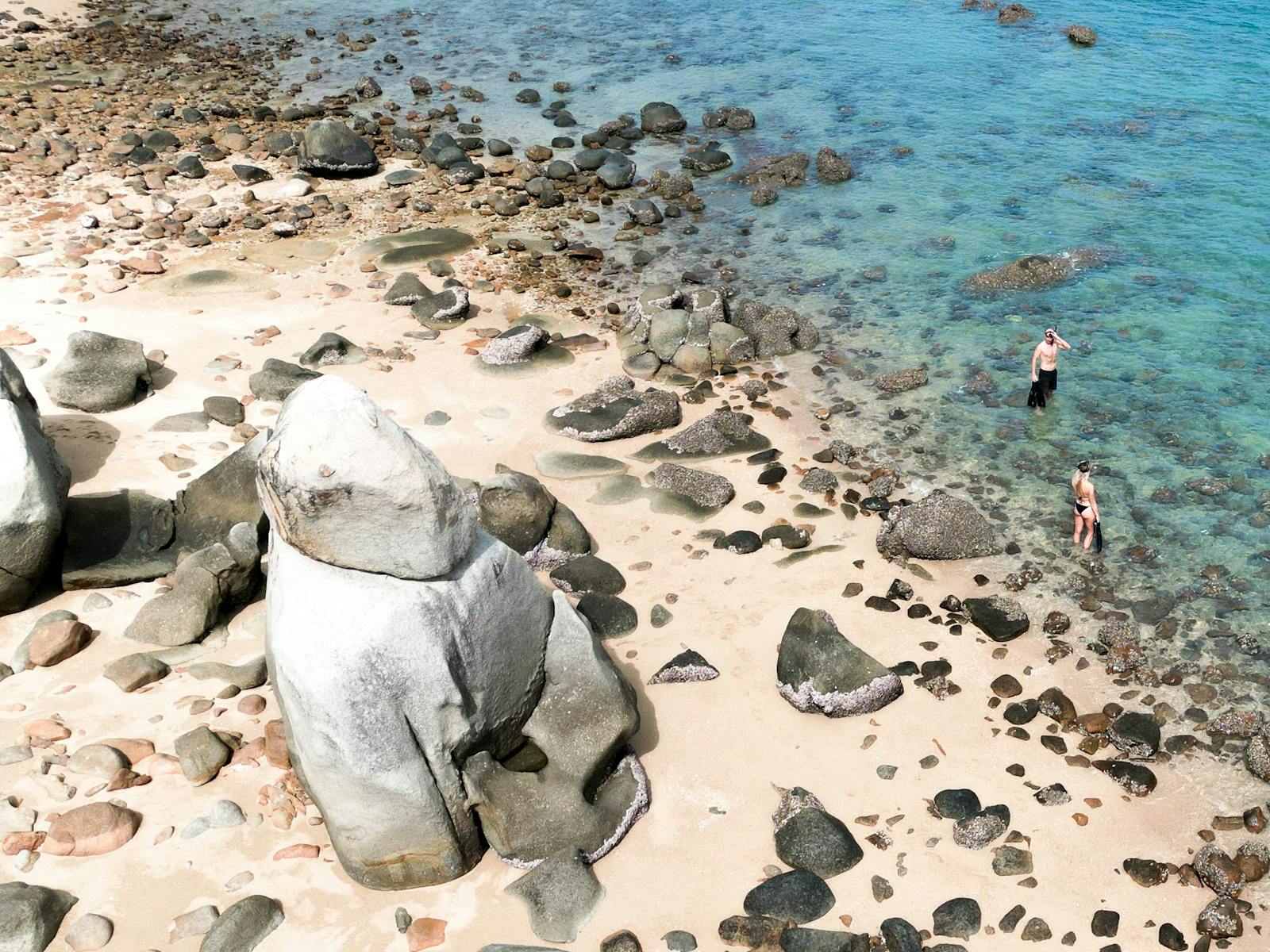 People with snorkelling gear heading to the crystal clear water at Hydeaway Bay