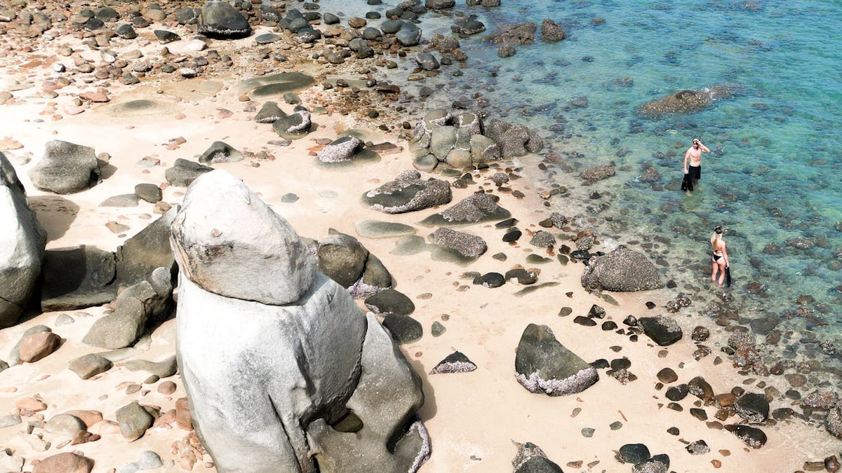 People with snorkelling gear heading to the crystal clear water at Hydeaway Bay