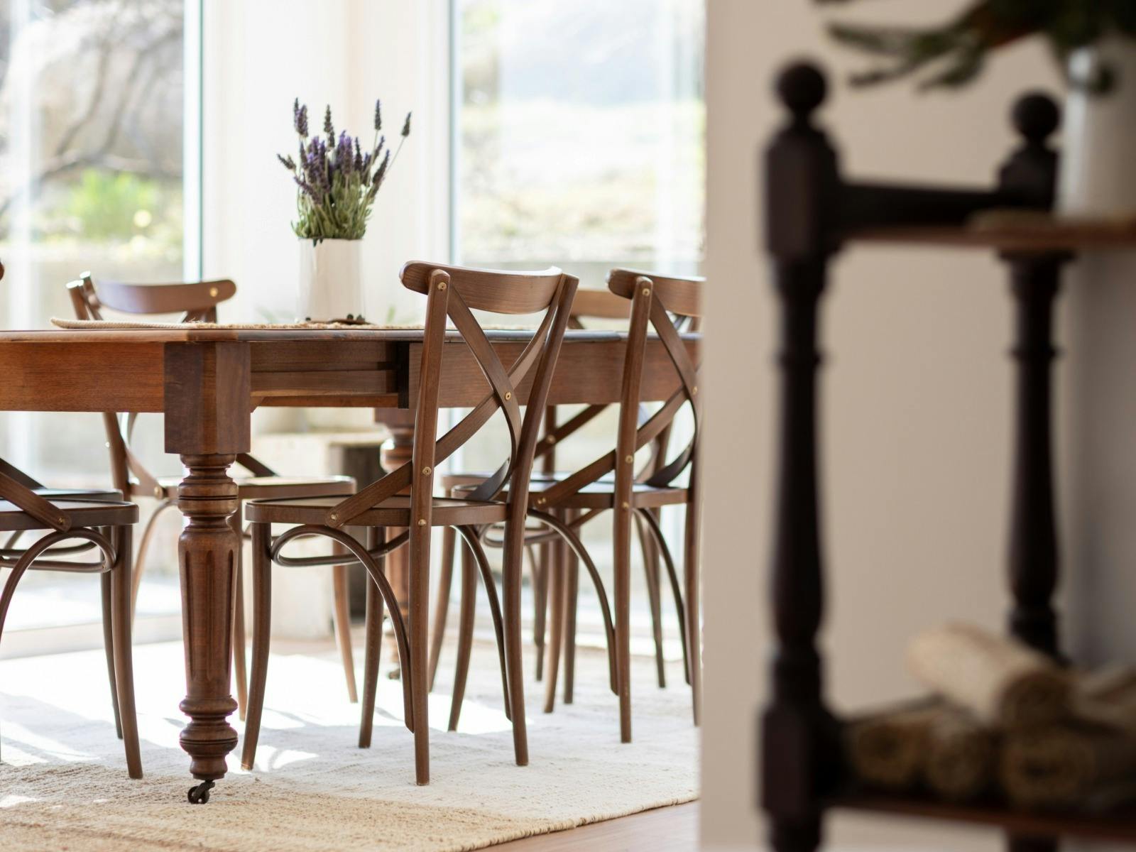 A six seated dining room table space, surrounded by windows looking outside.