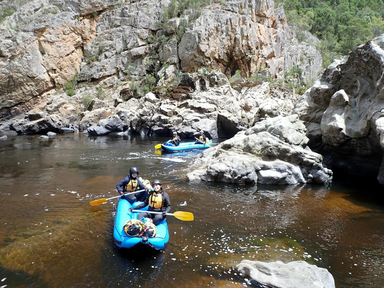 two people are rafting past a water carved rock formation on the Snowy River