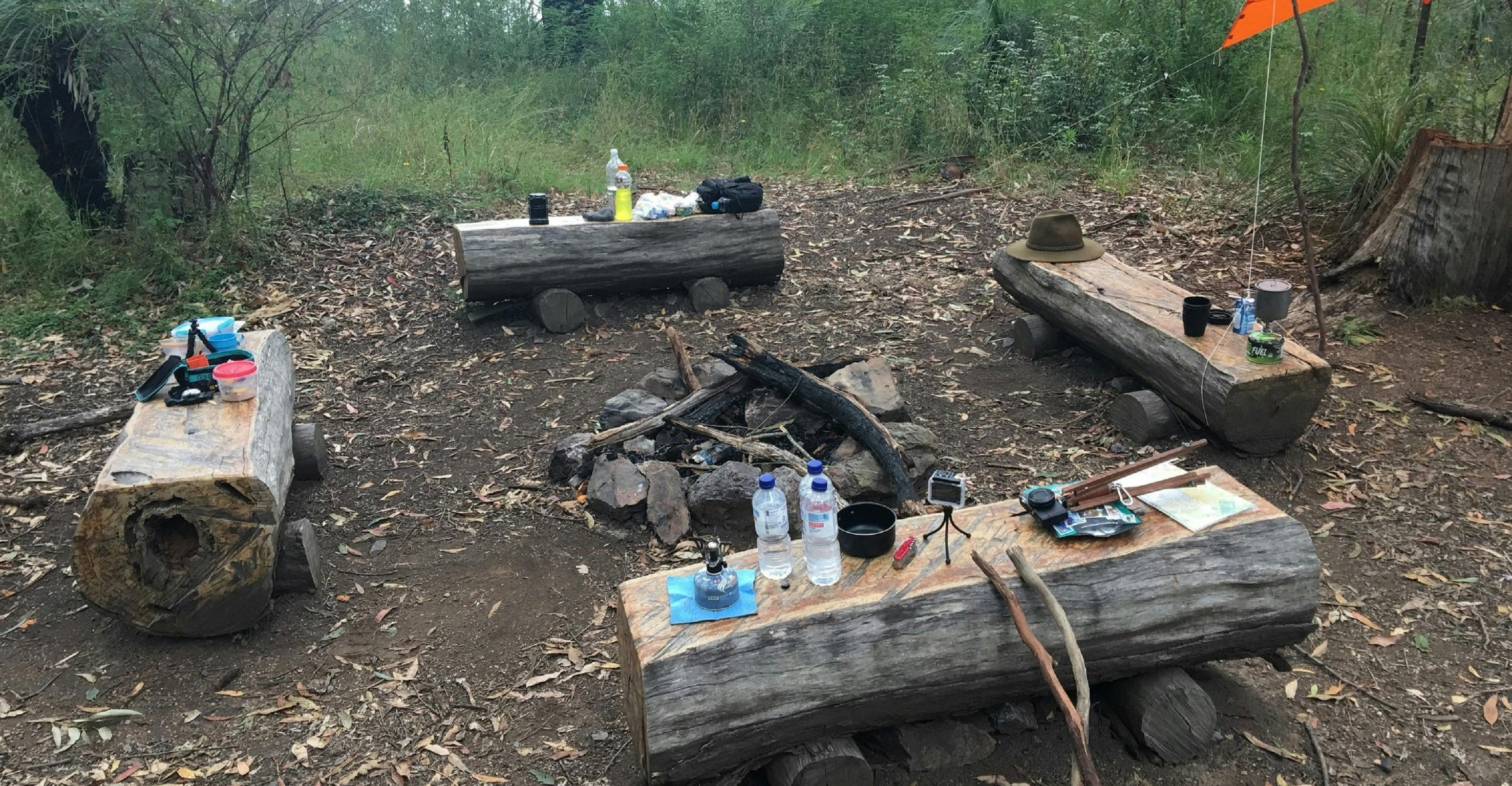 Four wooden bench seats surrounding a campfire spot in Northbrook Mountain Bush Camp