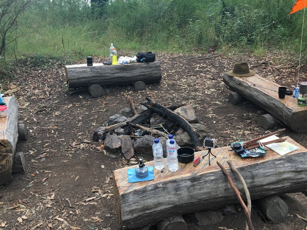 Four wooden bench seats surrounding a campfire spot in Northbrook Mountain Bush Camp
