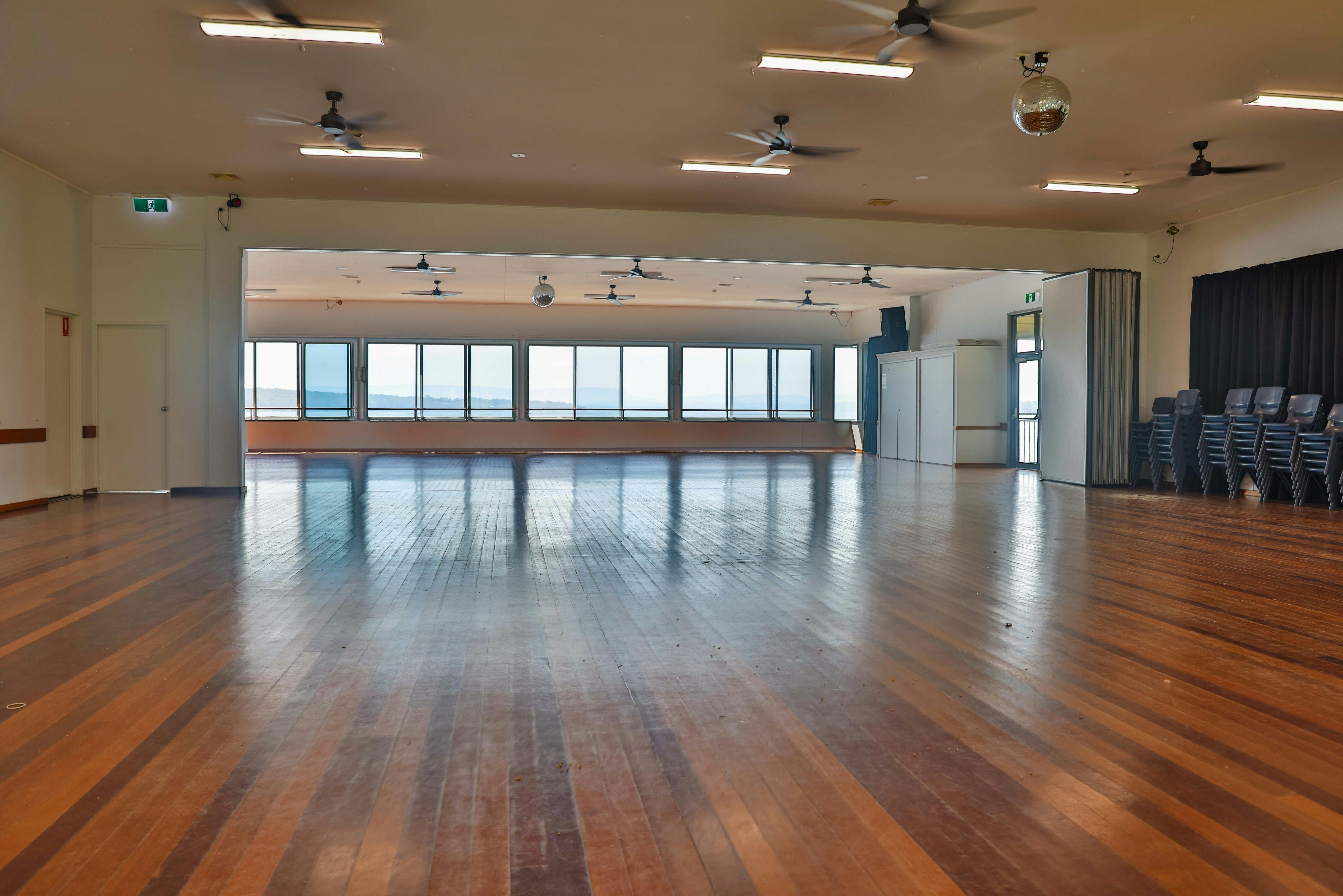 Large open hall with floorboard, windows and ceiling fans
