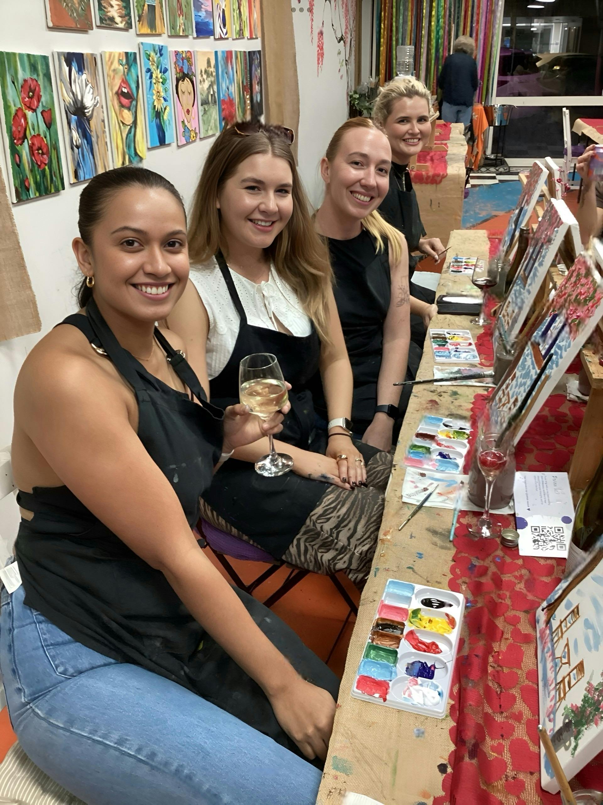LAdies enjoy a wine while they are painting their masterpeices..