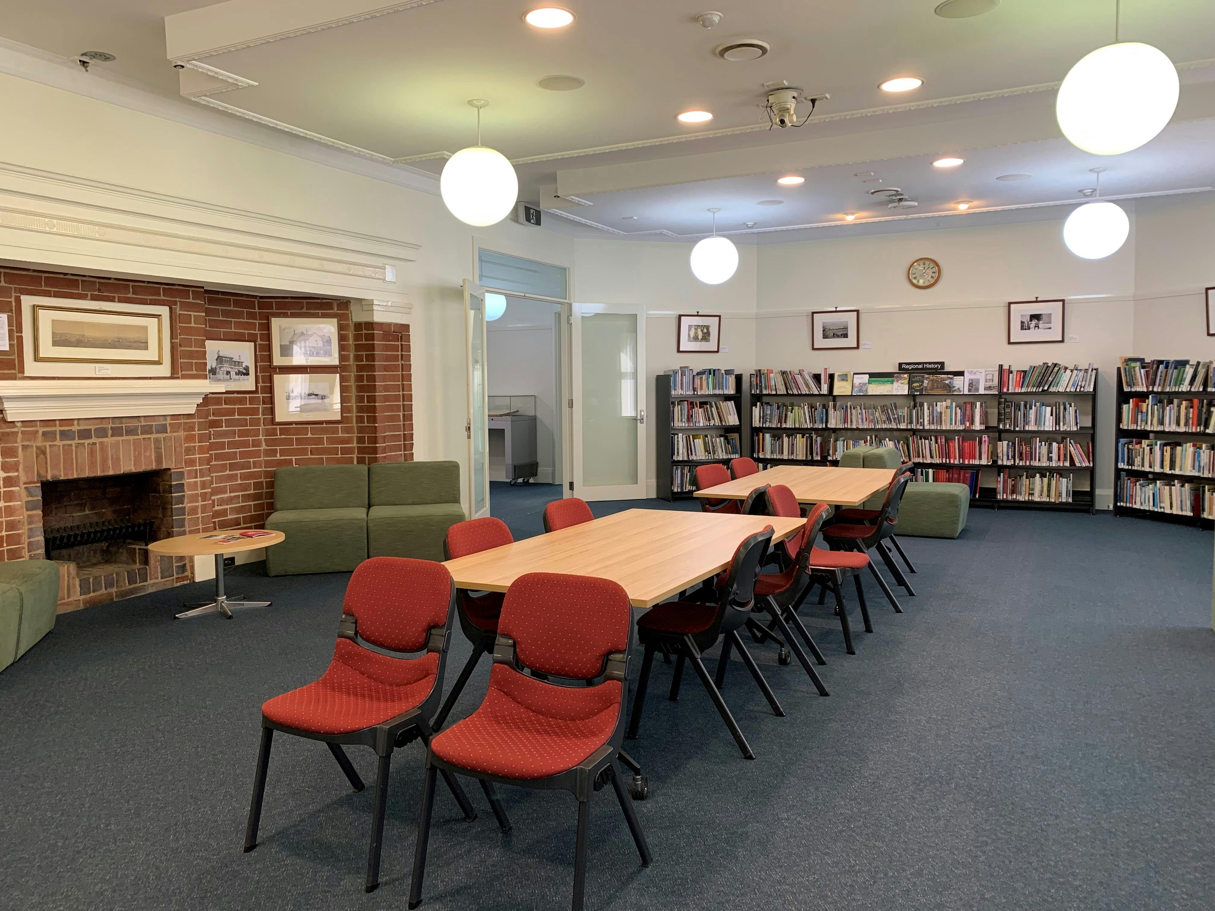 Image of large reading room with table and chairs, book shelves and round suspended lights