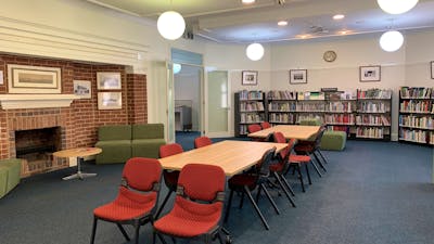 Image of large reading room with table and chairs, book shelves and round suspended lights