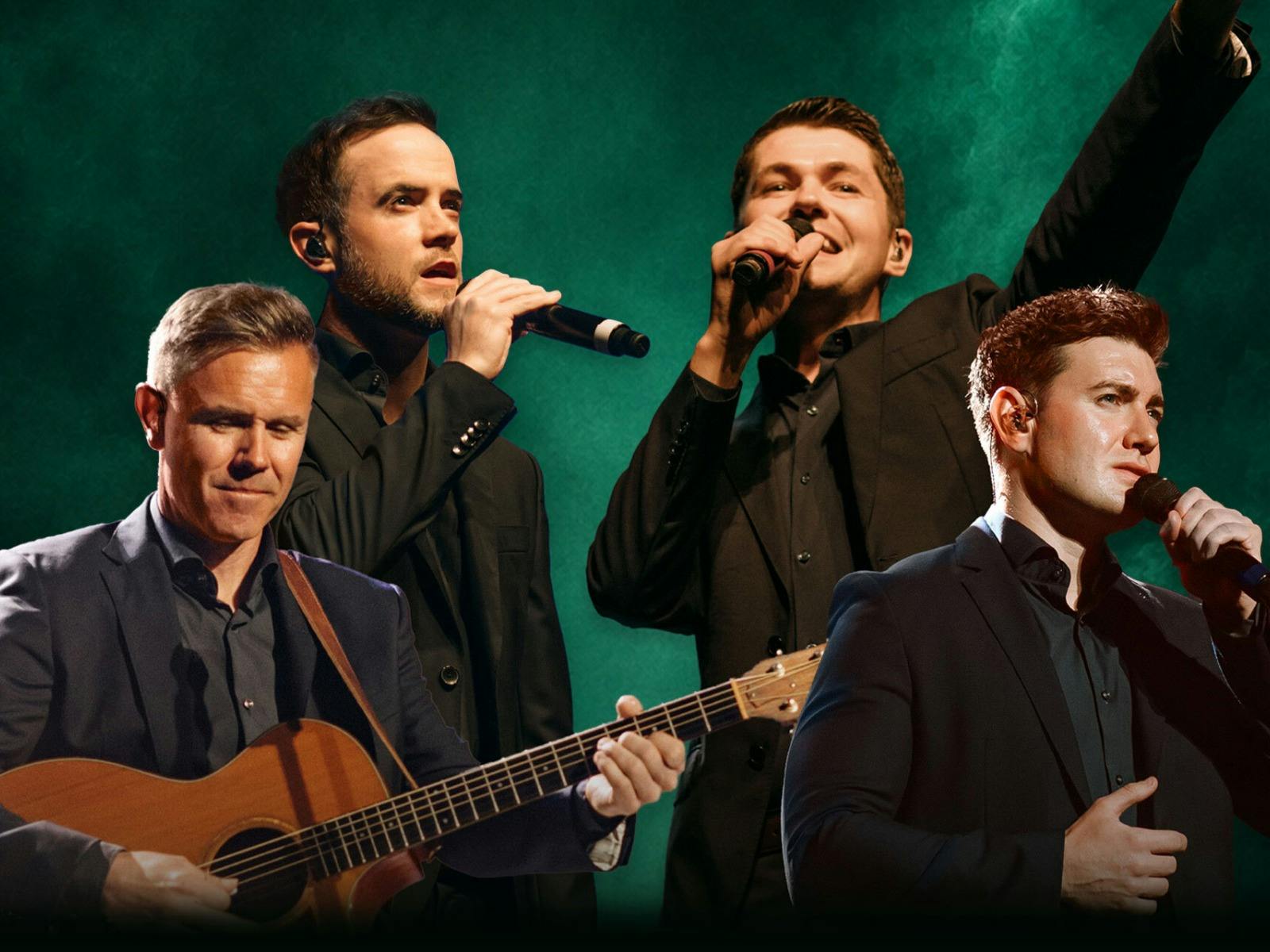 Four men perform on stage in dark suits against a green backdrop, singing into microphones.