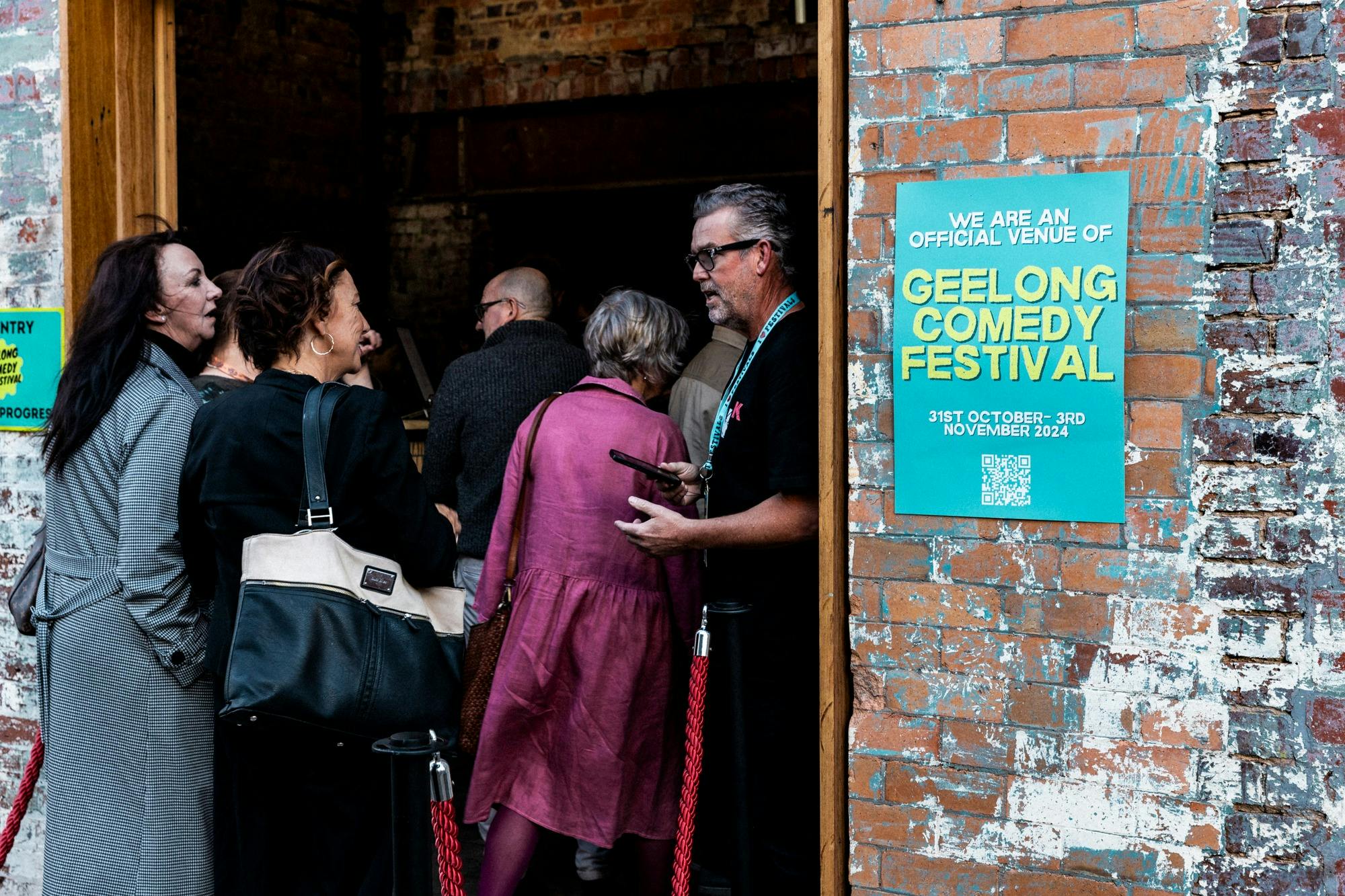 A line of people beong ushered into a room by a volunteer in a lanyard