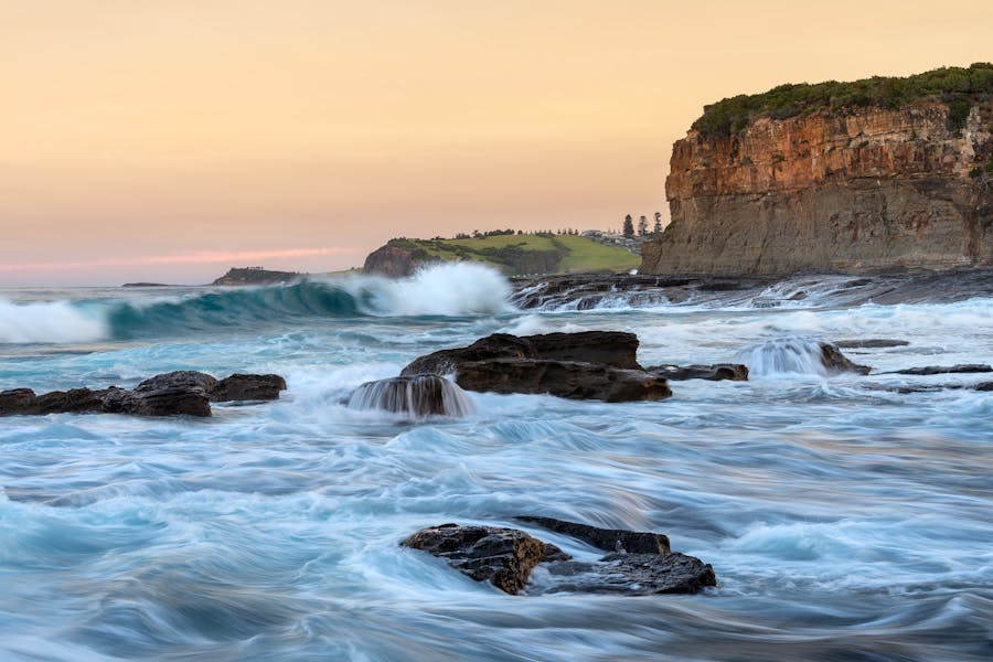 Silky waves roll into a bay with Gerringong in the background