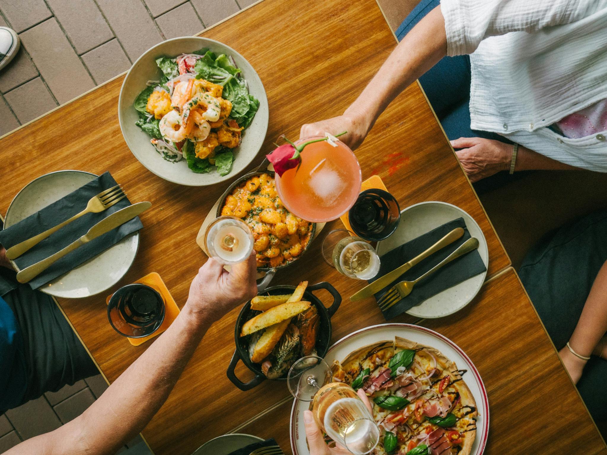 Image of two people gathered around a table that is laden with a variety of Italian foods