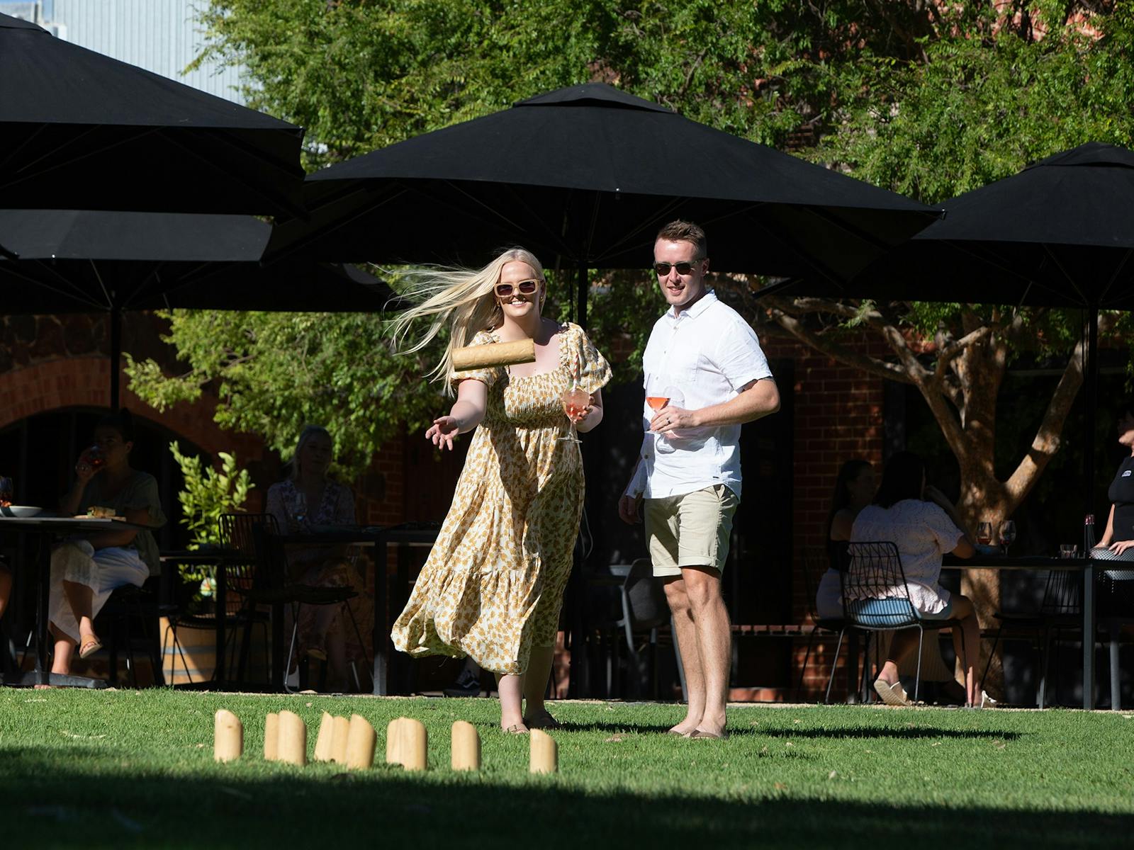 A couple play lawn games in Harry's Garden with a drink in hand