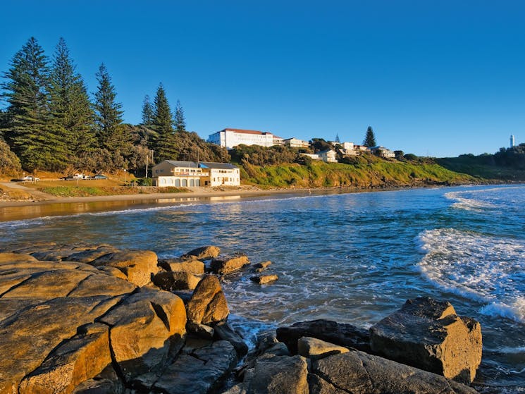 Rocks on waters edge with buildings in foreground