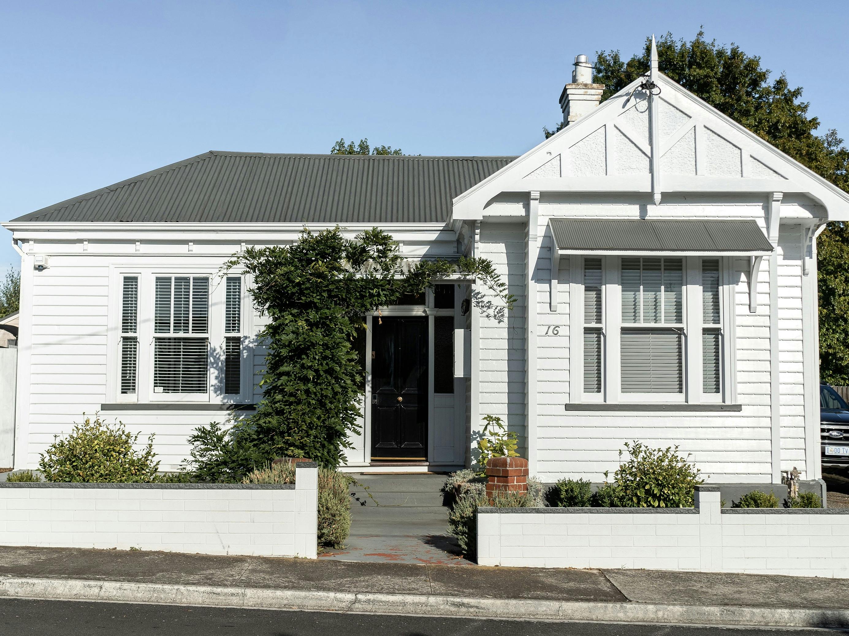 White weatherboard house, federation style, climbing wisteria, blue skies.
