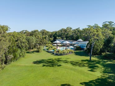 Aerial view of the leisure centre, large village green, pool, and surrounding bushland.