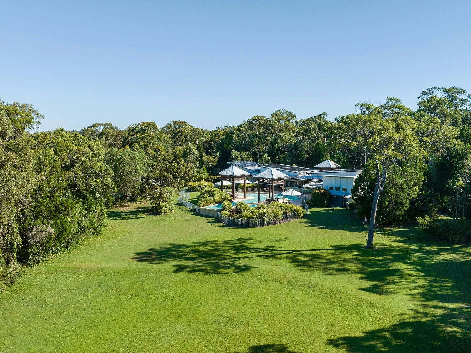 Aerial view of the leisure centre, large village green, pool, and surrounding bushland. Aerial view of the leisure centre, large village green, pool, and surrounding bushland.