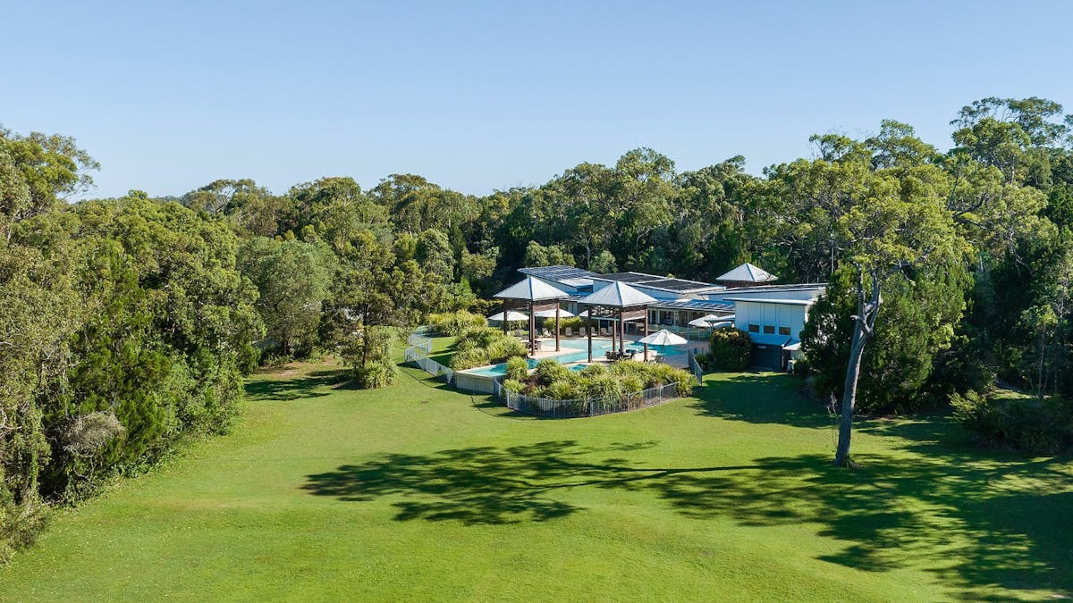 Aerial view of the leisure centre, large village green, pool, and surrounding bushland.