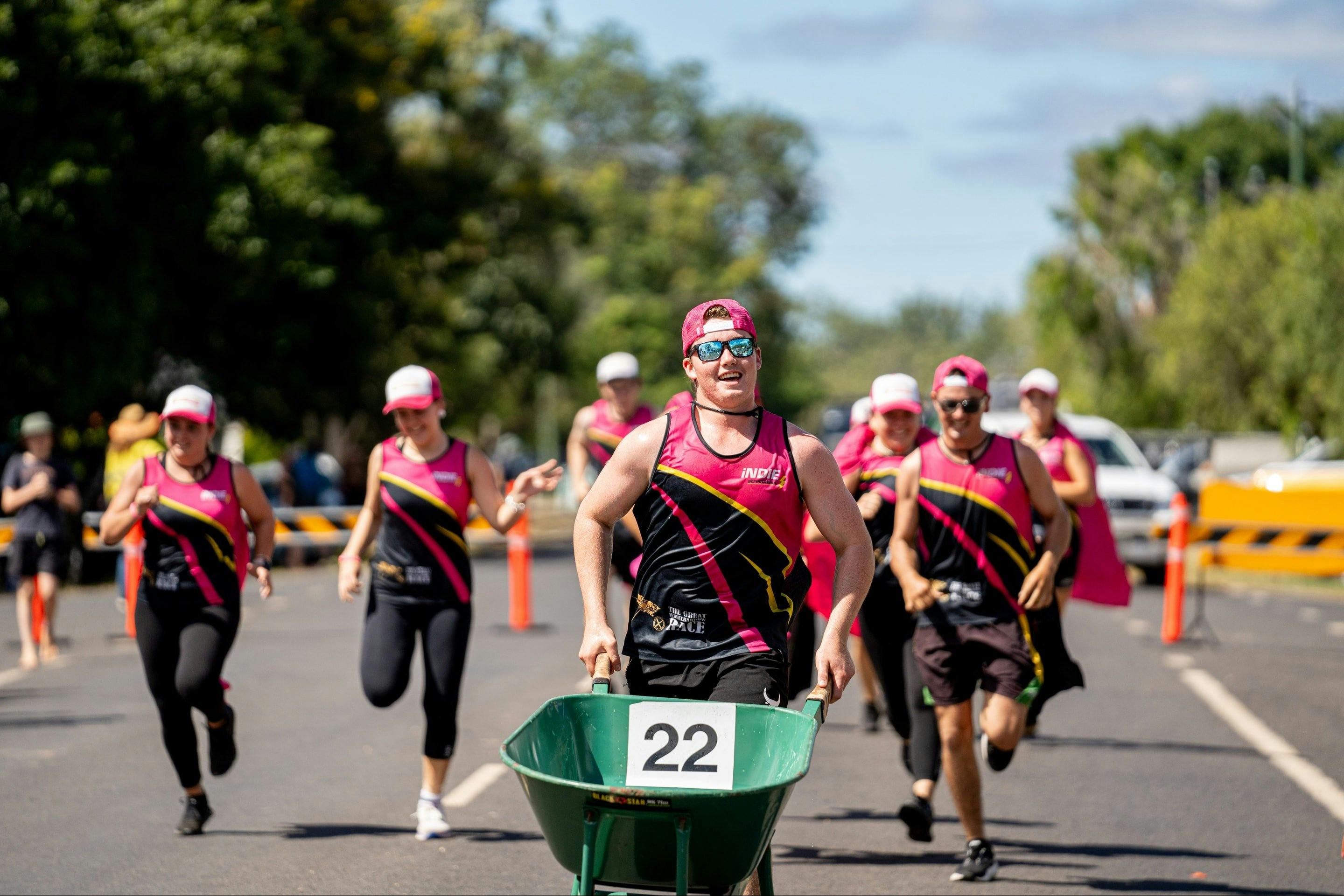 A team in pink and black run for the finish line in The Great Wheelbarrow Race, Mareeba, FNQ.