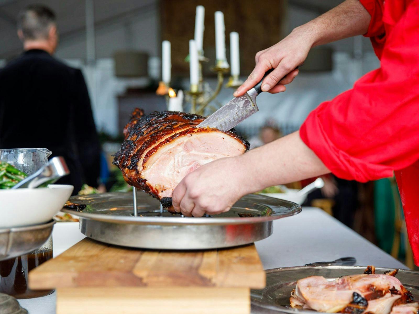 Someone carving a leg of ham