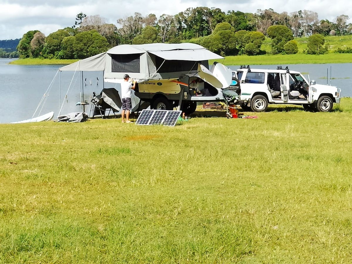 4WD and camper trailer on grassed edge of lake.