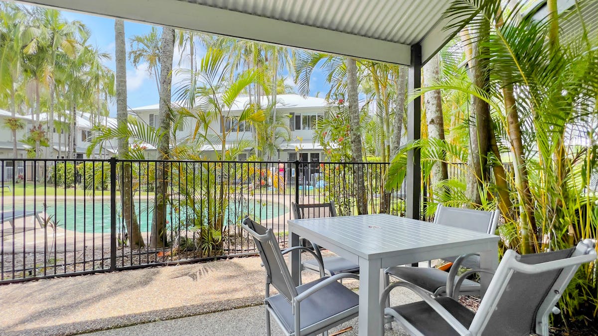 Table and chairs outside with view of the pool