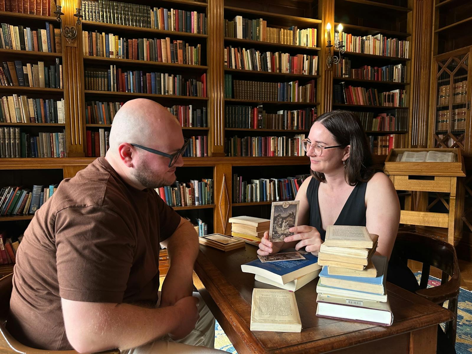 Two people at a table with books around them