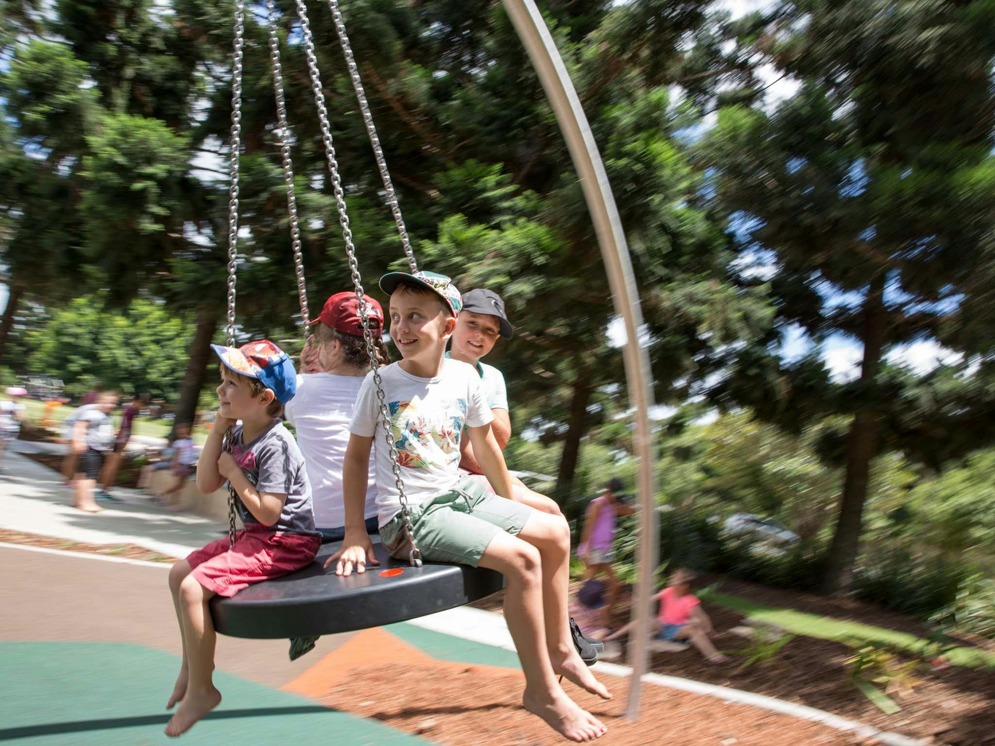 Four kids sitting on a large round swing at Pine Rivers Park Four kids sitting on a large round swing at Pine Rivers Park