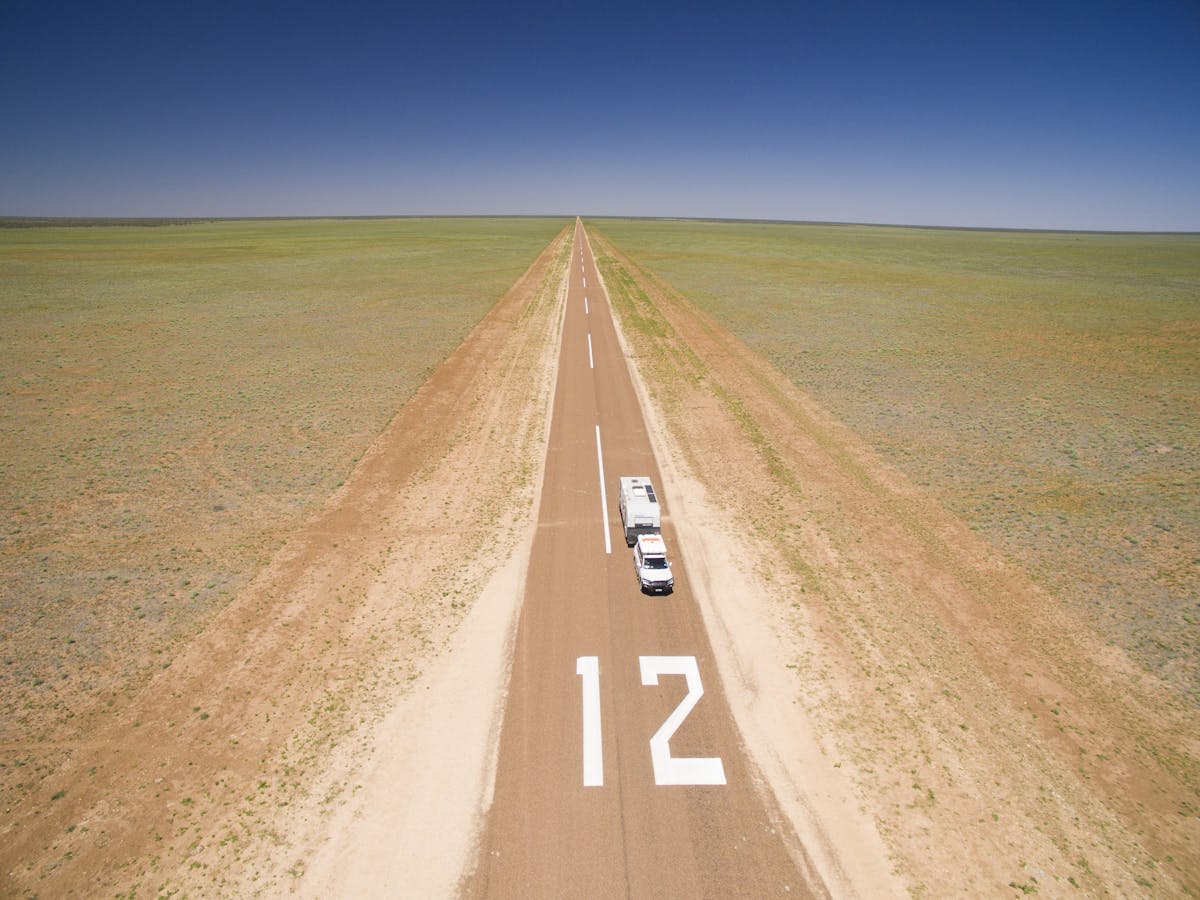 4WD Vehicle towing a Caravan along a long stretch of the Warrego highway in Outback Queensland