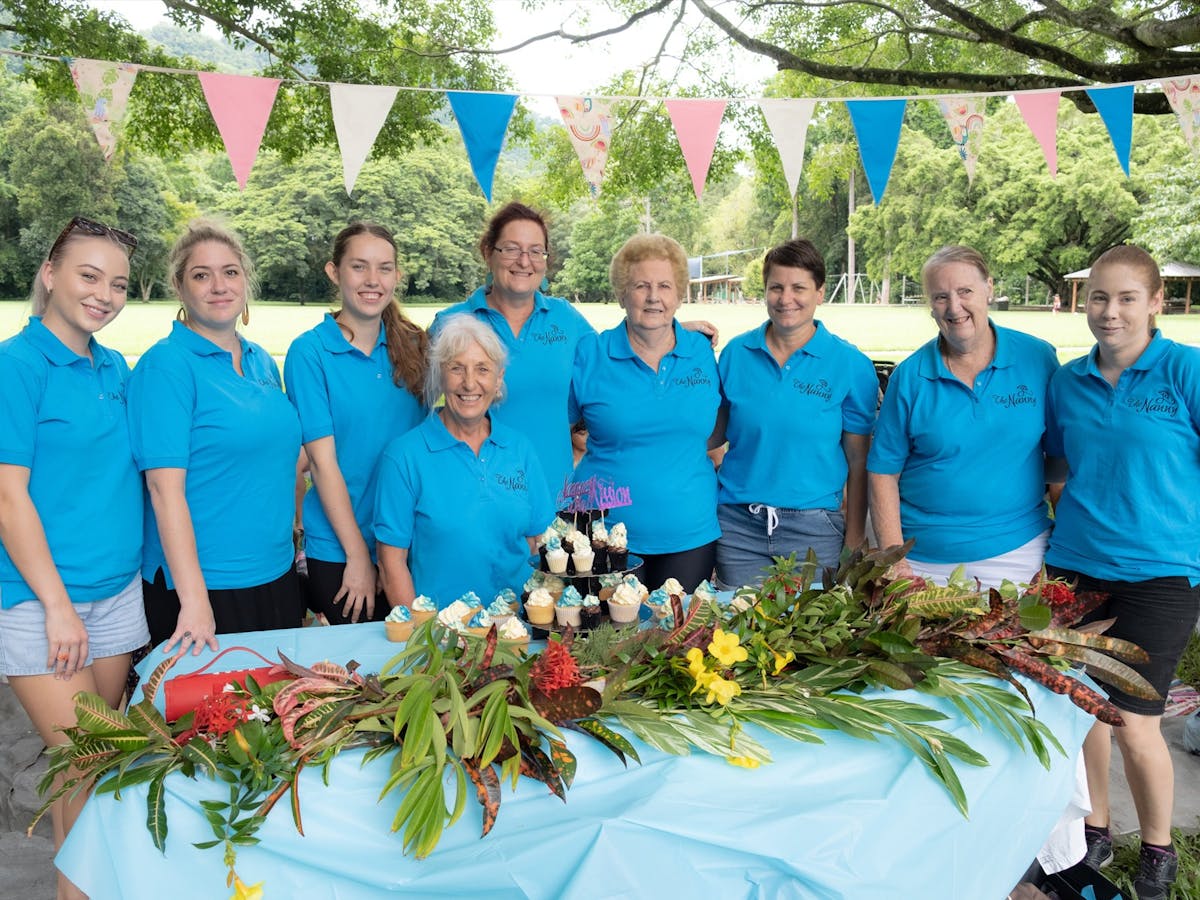 Image of Nannies On A Mission Team in a row behind a table with flowers on it.