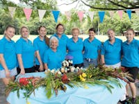 Image of Nannies On A Mission Team in a row behind a table with flowers on it.