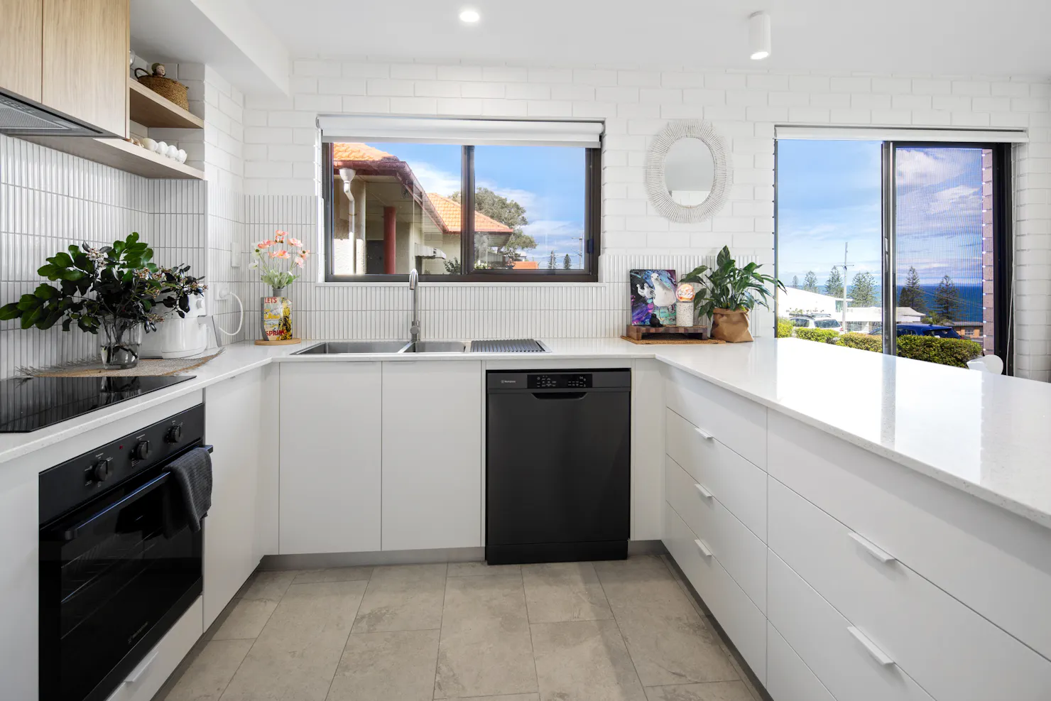 interior of modern clean white spacious kitchen with cook top, dishwasher and air fryer