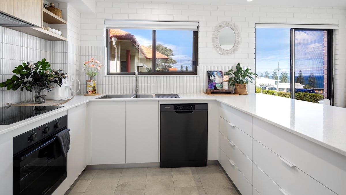 interior of modern clean white spacious kitchen with cook top, dishwasher and air fryer