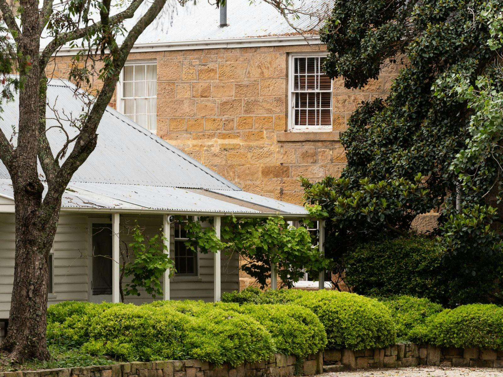 A white weatherboard building and sandstone building from the mid 1800s