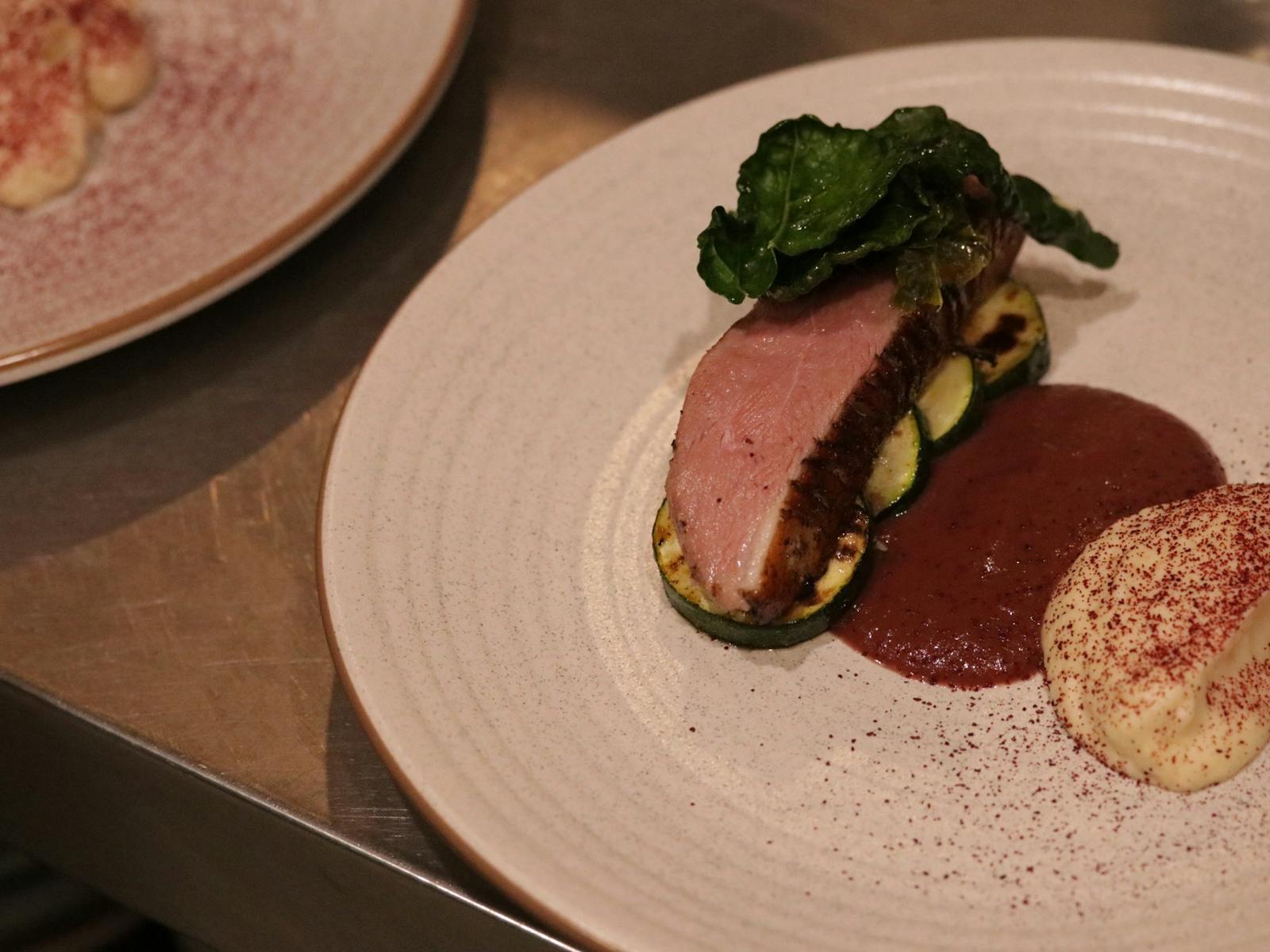 Duck Breast Sliced cooked medium resting on Grilled Zucchini with a fermented Plum Sauce and Powder