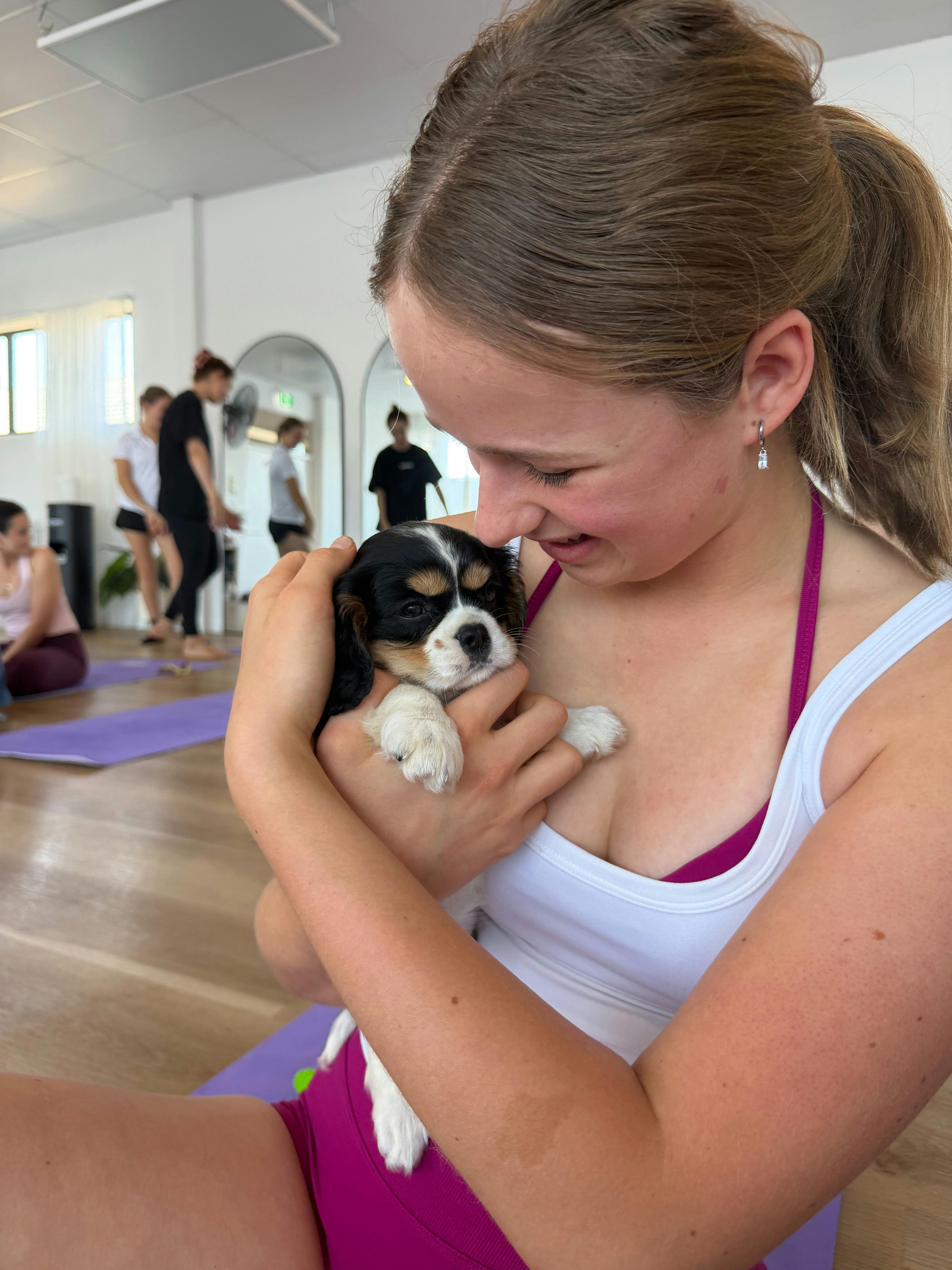 A participant enjoying puppy cuddles at Yoga Paws on the Sunshine Coast.