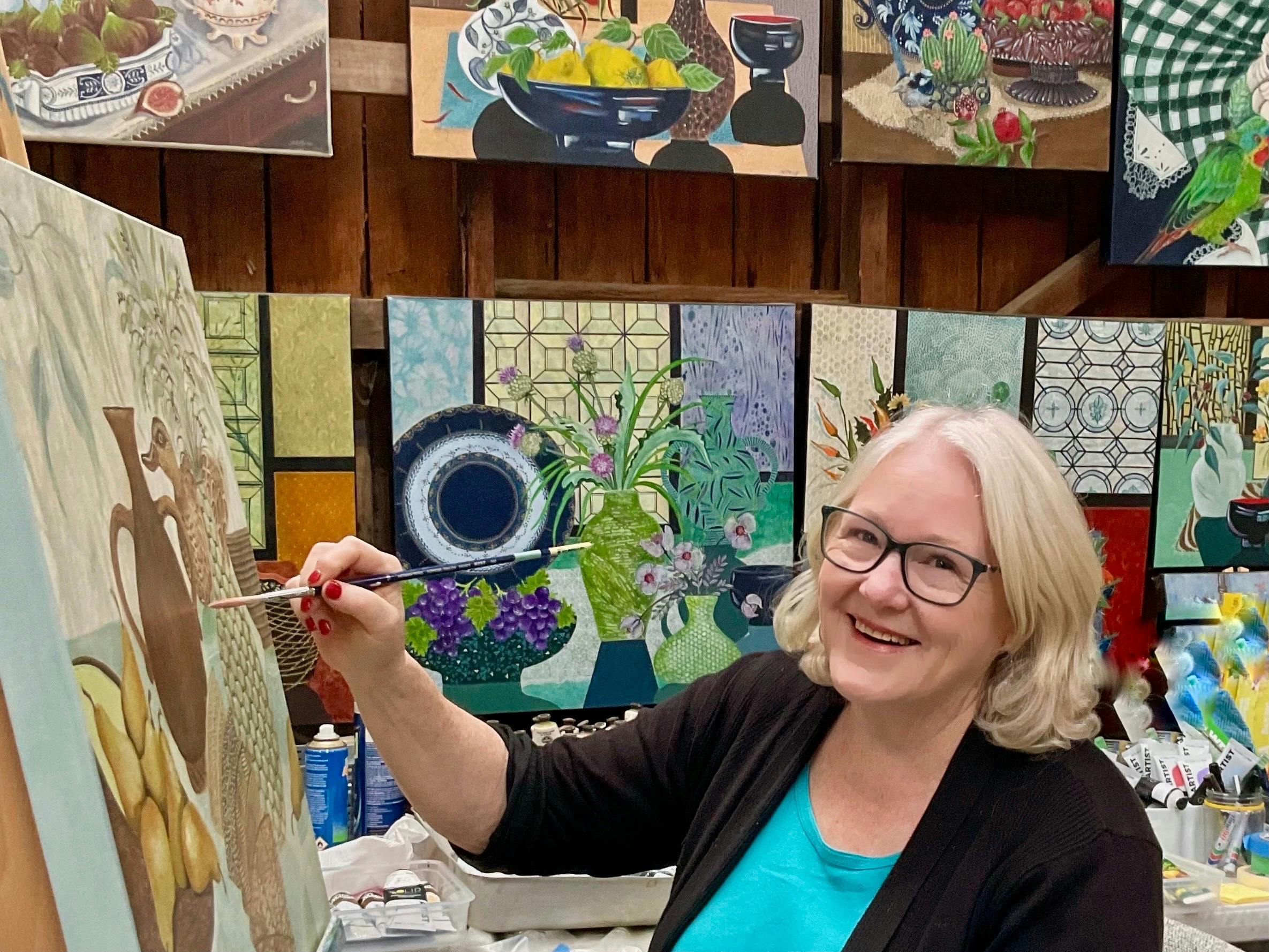 A female artist painting in her studio surrounded by her art