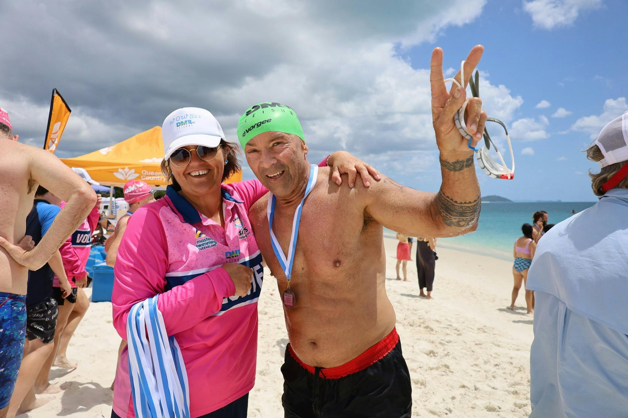 swimmer with arm around finish line volunteer smiling after getting presented with medal