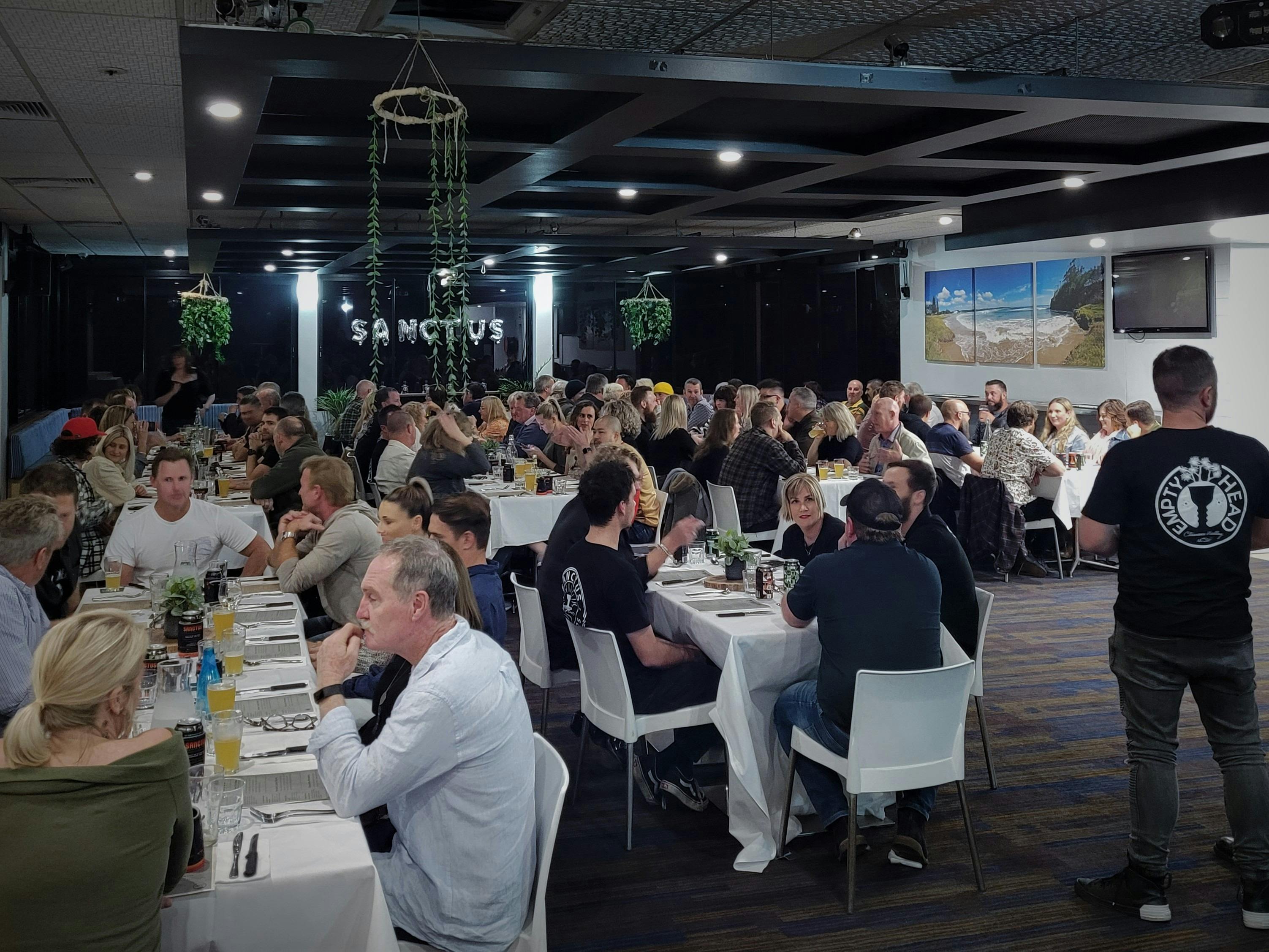 Function room with people sitting at long tables talking and laughing