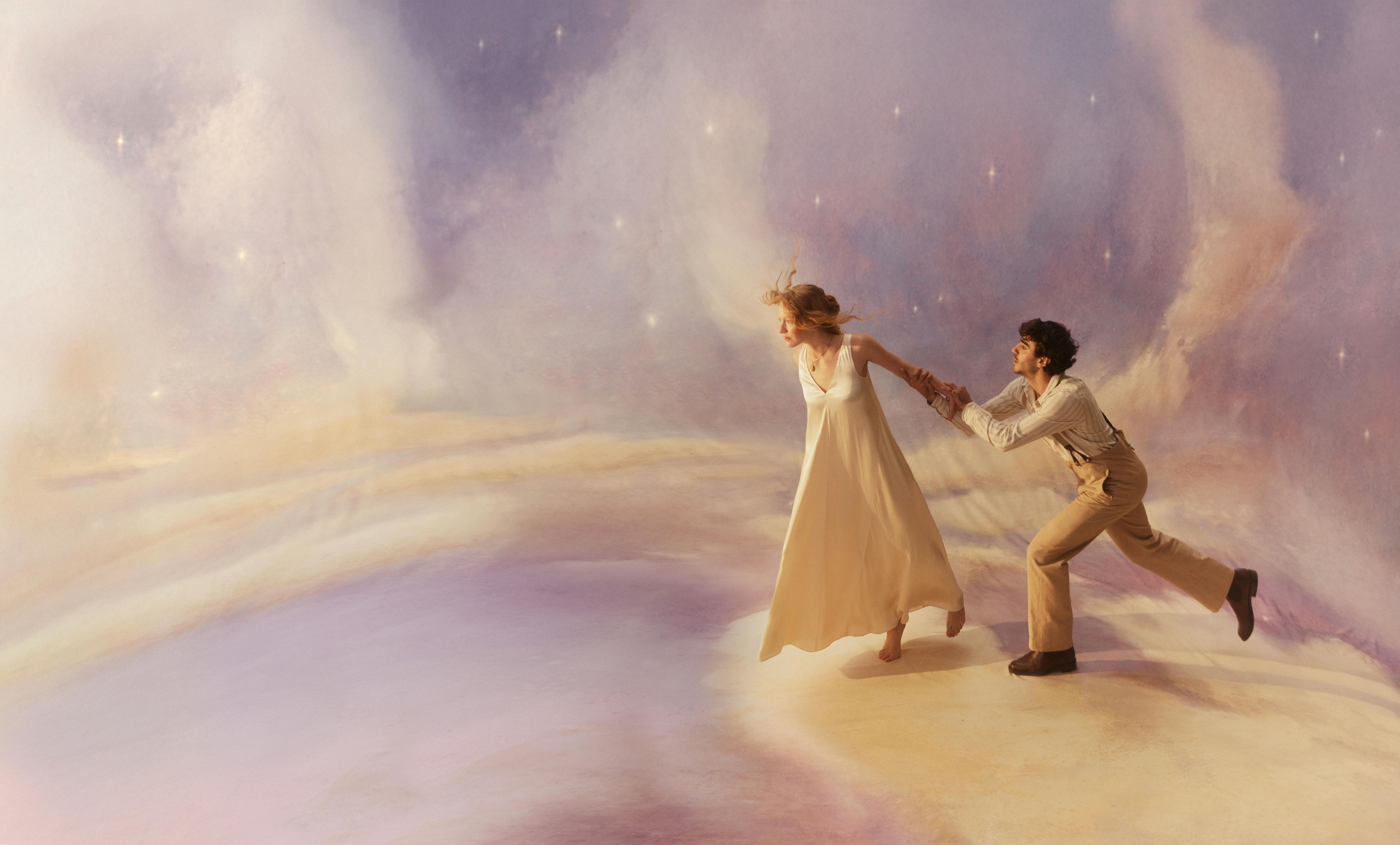 A woman in a white dress pulls a man across a dreamy, starry landscape.