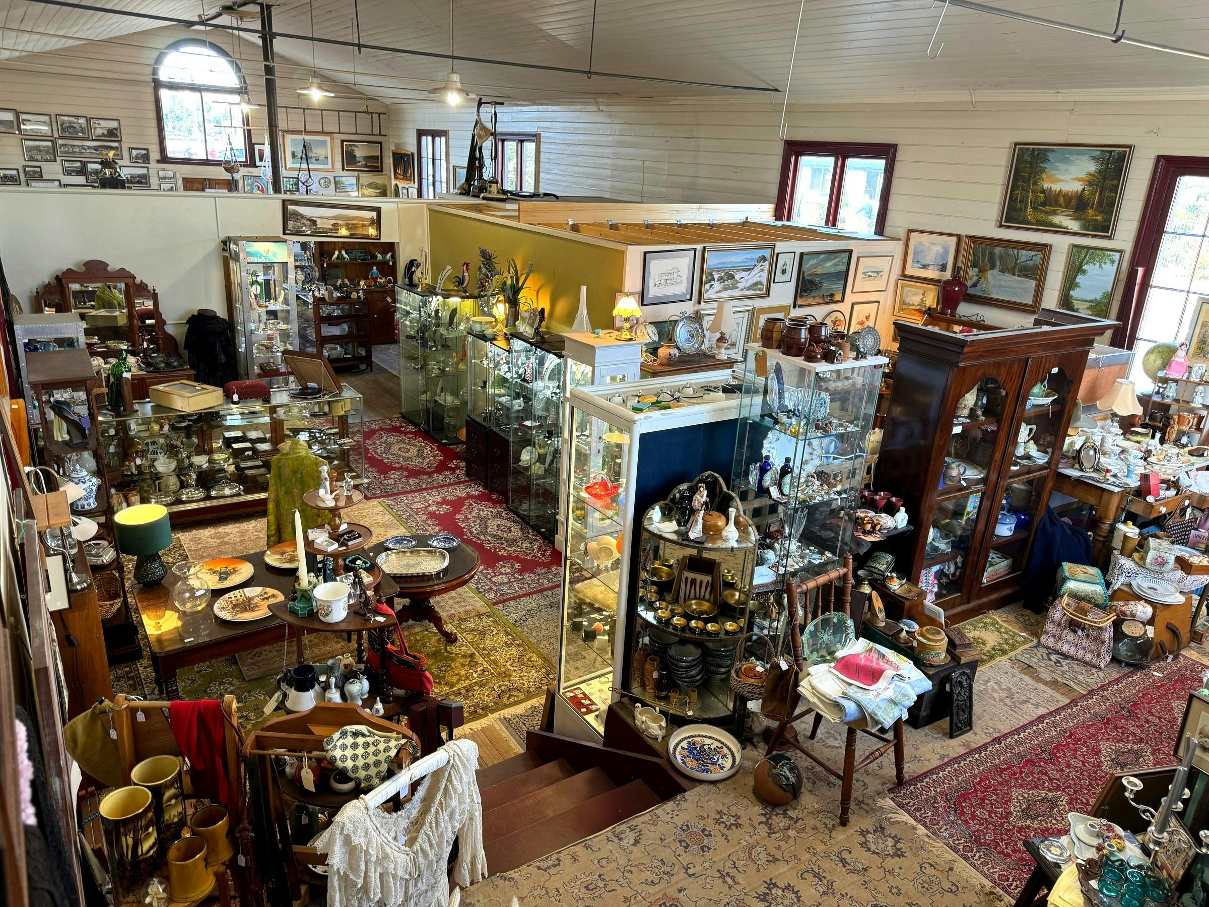 Wide view of antique shop interior with timber cabinets, rugs, and display cases