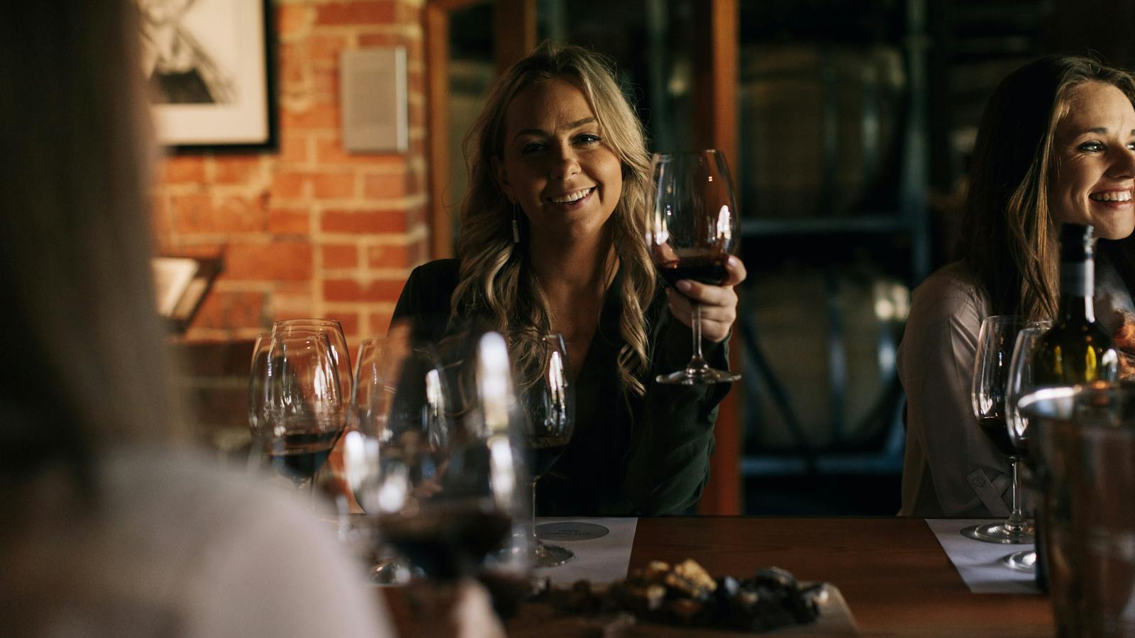 A guest raises her glass of red wine  in Trott's Cellar