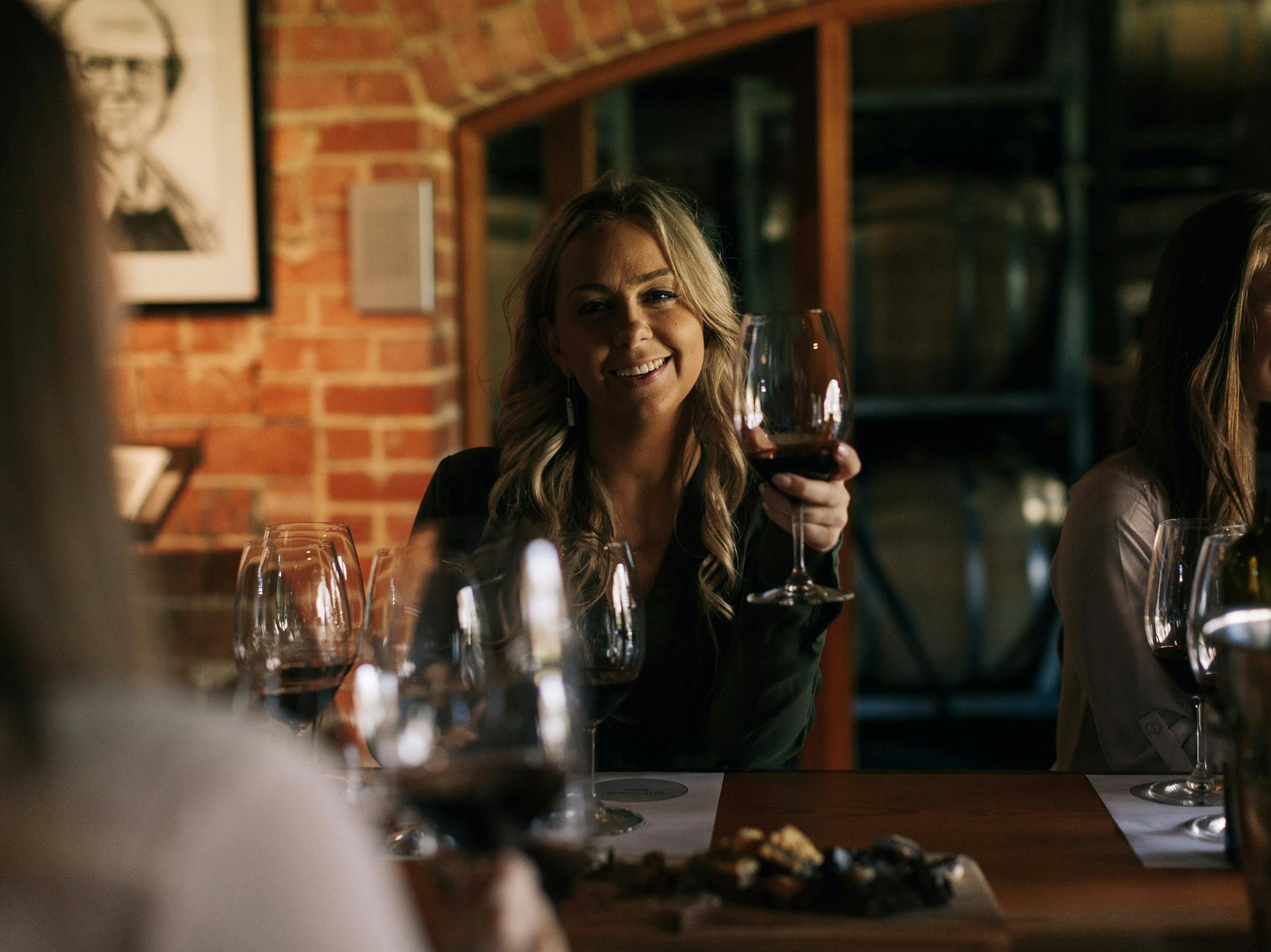 A guest raises her glass of red wine  in Trott's Cellar